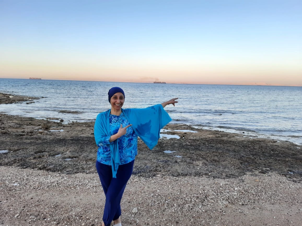 Abeer standing on the beach with a huge smile.