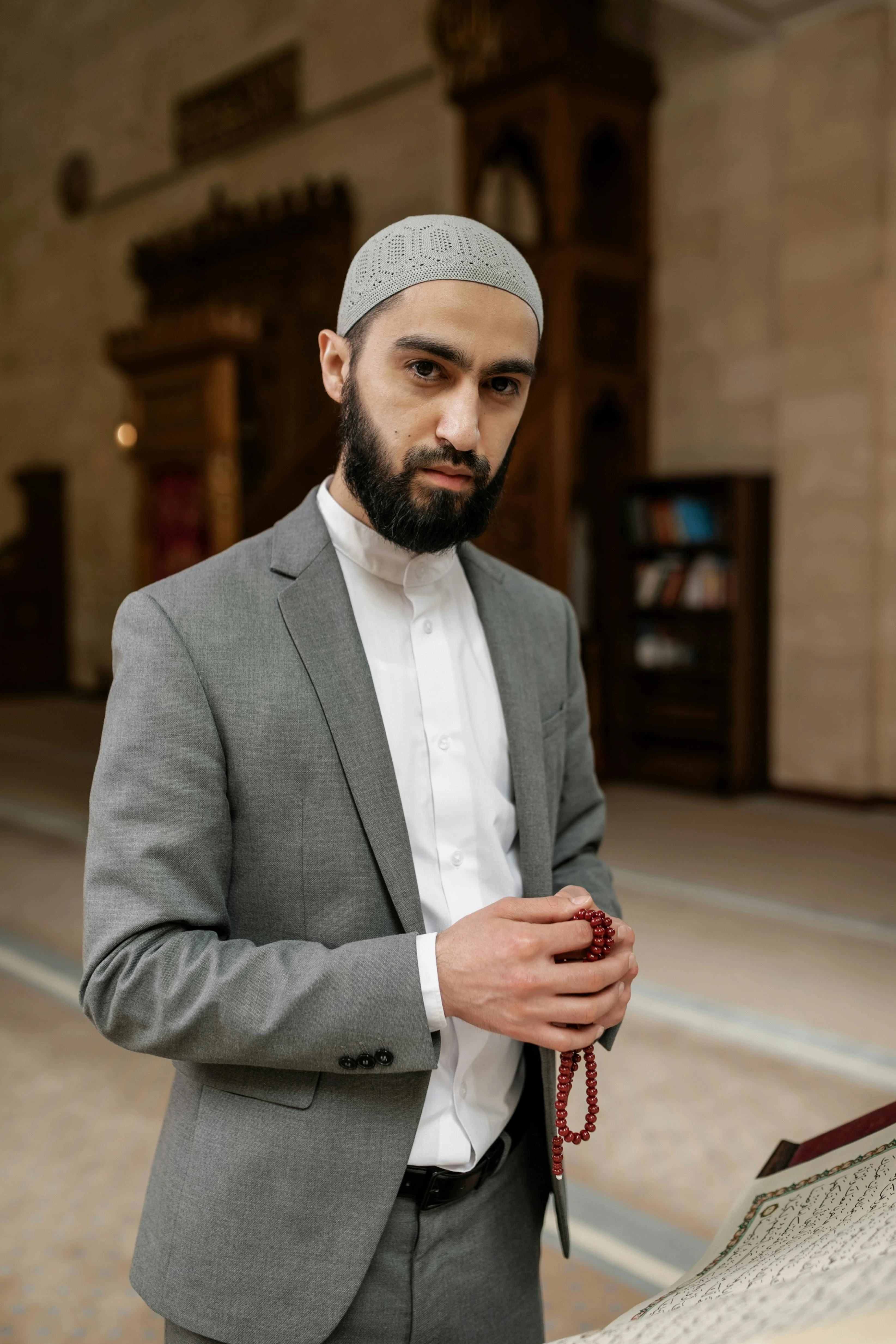 An imam who stands in a mosque and looks at the camera.